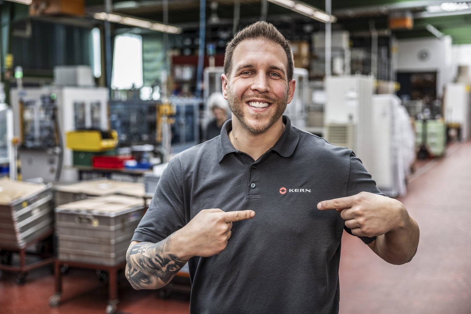 Mitarbeiterprotrait Kern Antriebstechnik Mitarbeiter zeigt auf Logoaufdruck auf T-Shirt von Kern Antriebstechnik